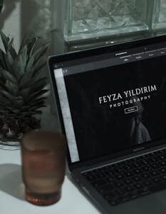 An aesthetically pleasing workspace featuring a laptop with a photographer's website, surrounded by minimalist decor.