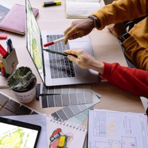 High angle view of designers collaborating on project with laptop and color swatches at desk.