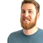 Close-up of a smiling bearded man in a casual blue shirt against a white background.
